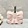 A pink ceramic pump dispenser with a silver pump mechanism sitting on a gray surface.