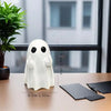 A white ghost resin statue with a middle finger gesture is displayed on a wooden table.