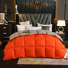 Orange down comforter with a white cotton cover resting on a bed in a dark room.