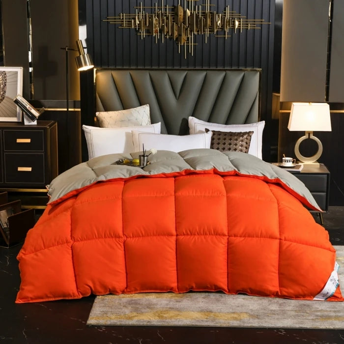 Orange down comforter with a white cotton cover resting on a bed in a dark room.