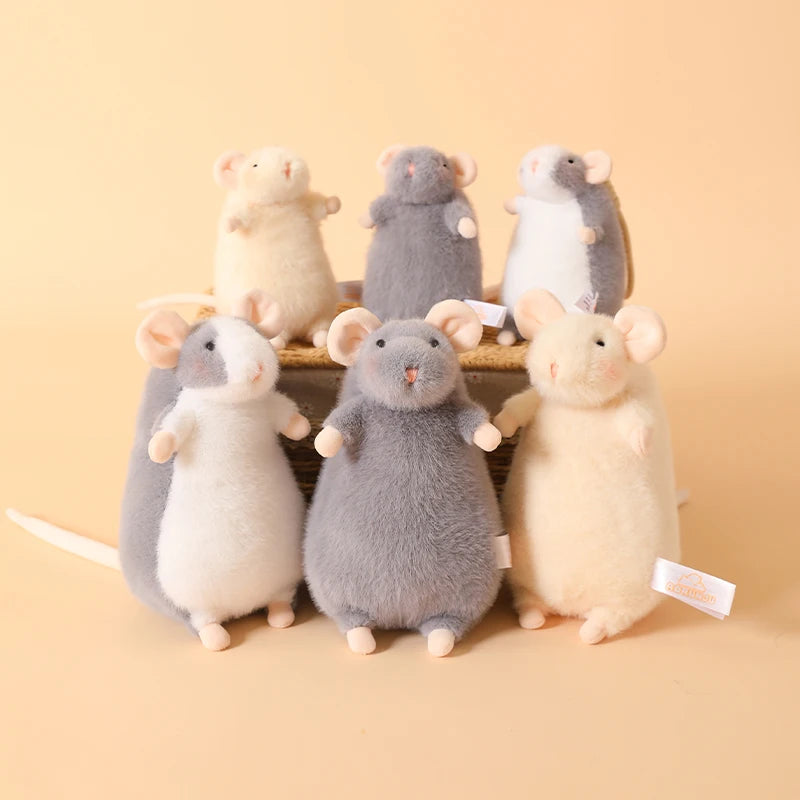 A collection of five adorable plush mouse stuffed animals in various shades of gray and cream sitting on a wooden surface.