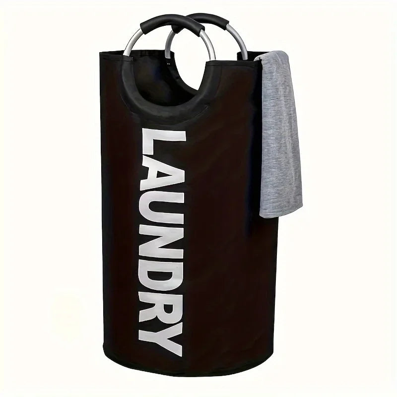 A dark brown foldable laundry basket with padded handles and a gray towel hanging over the side.