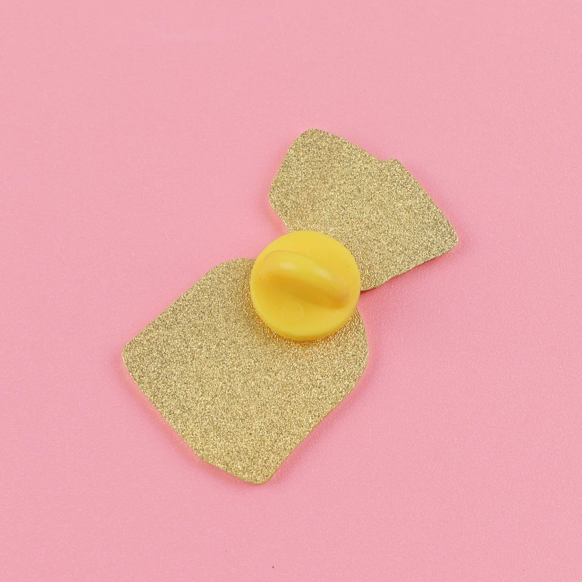 A gold glitter enamel pin shaped like a strawberry is displayed on a pink background.