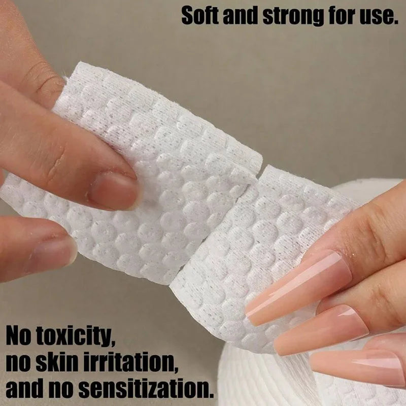 A hand is holding a white lint-free cotton round for nail care, demonstrating its soft and strong texture.