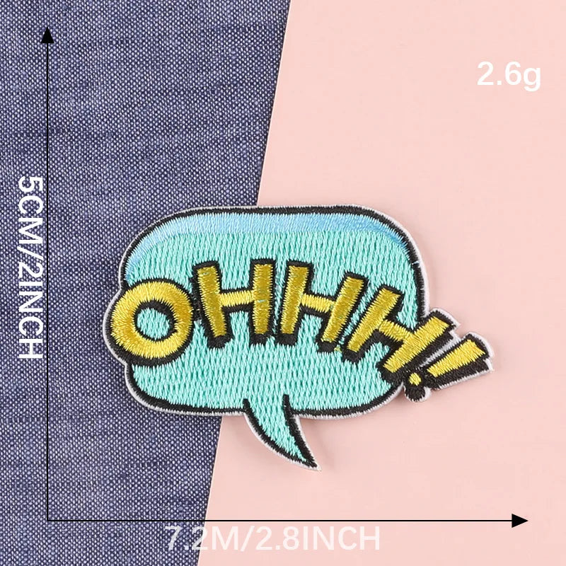 A teal embroidered lettering patch shaped like an exclamation mark on a gray fabric background.