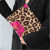 A black blazer sleeve holds a leopard print floral tablet case with pink flowers.