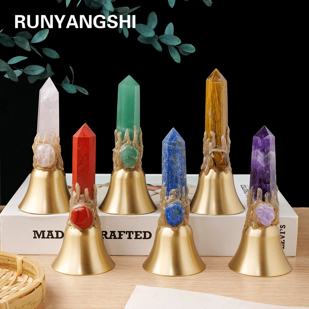 Five natural crystal points in various colors mounted on brass bells displayed on a white box.