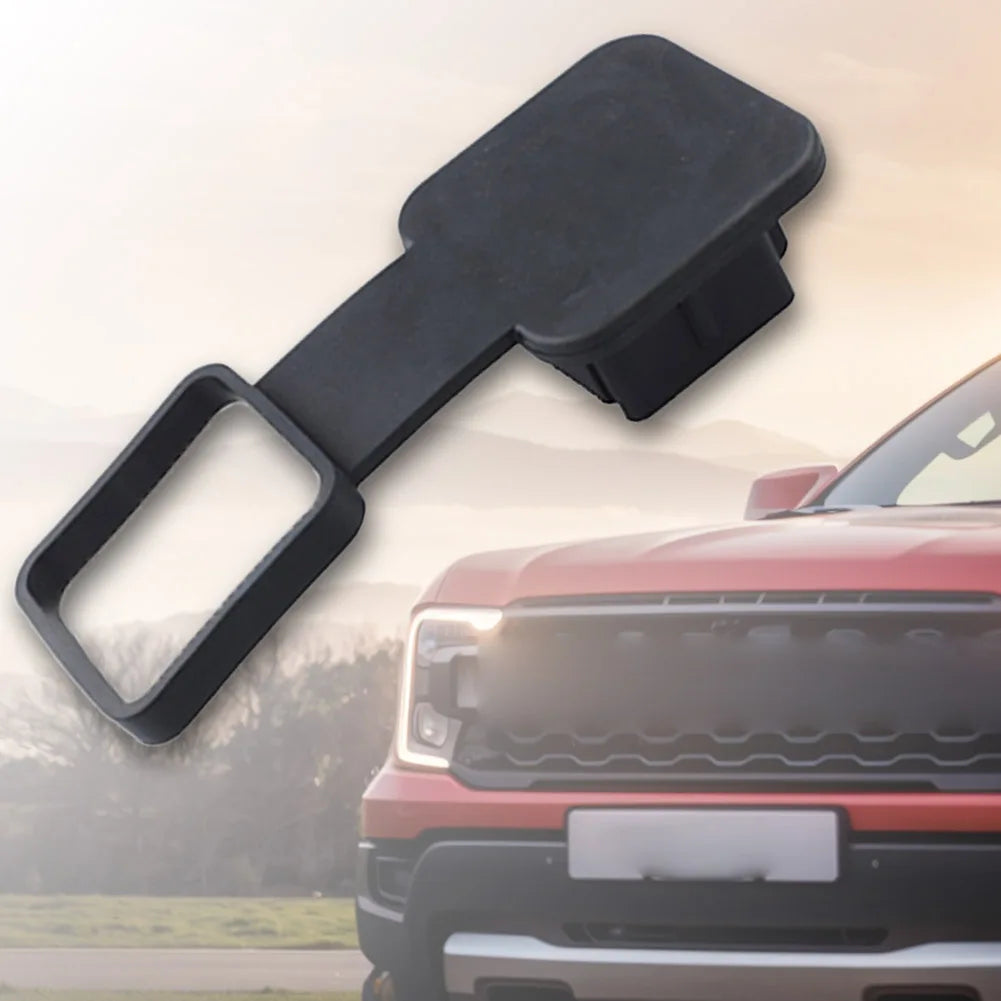 Black trailer hitch receiver cover with a flag emblem shown next to a red pickup truck.