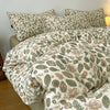 A beige and green floral printed duvet cover set with matching pillows on a bed.