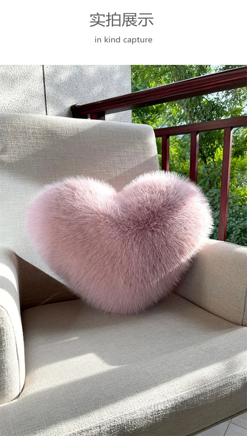 A fluffy pink heart-shaped throw pillow resting on a light-colored sofa.