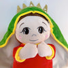 A soft plush toy of Jesus with a green hood and gold crown, featuring a red garment.