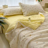 A yellow and white floral washed cotton gauze summer quilt with matching pillows and a yellow fabric accent.