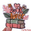 An embroidered patch featuring the text Book Lover surrounded by floral elements and a stack of books.