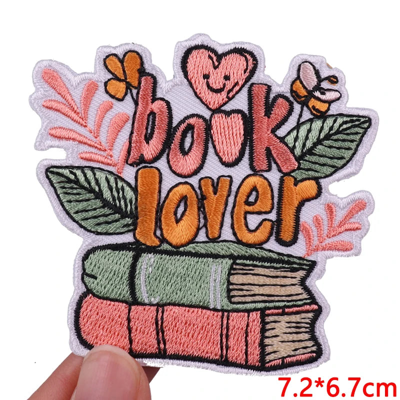 An embroidered patch featuring the text Book Lover surrounded by floral elements and a stack of books.