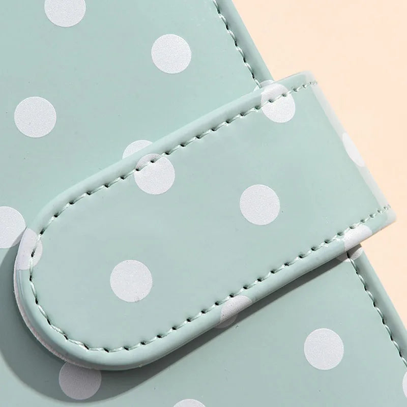 A light mint green binder wallet with white polka dots, showing the cover and a flap.