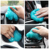 A hand is using a reusable turquoise cleaning gel to wipe down car interiors and electronics.