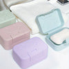 A collection of pastel colored smiley face lidded soap dishes and a white towel are displayed on a white surface.