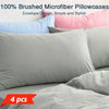 A set of four gray microfiber pillowcases with envelope design shown on a bed.