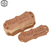 A stack of brown PU leather sewing labels with the text Hand made with Love stamped on them.