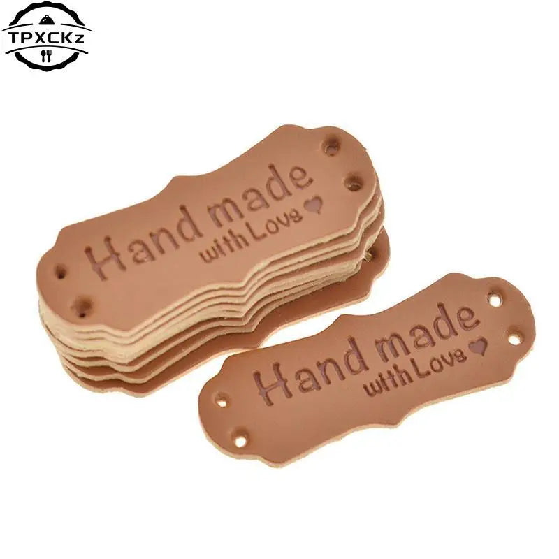 A stack of brown PU leather sewing labels with the text Hand made with Love stamped on them.