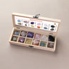 A wooden gift box containing twelve natural gemstone crystals arranged in compartments.