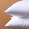 A stack of white square cushions with a smooth, rounded shape against a beige background.