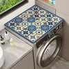 A close-up of a stainless steel washing machine with a blue and white floral print protective mat on the top surface.