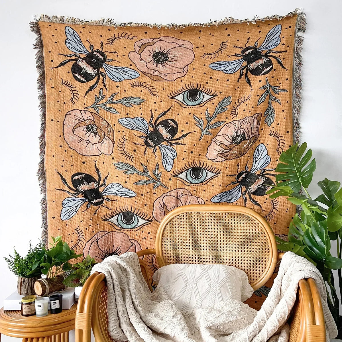 A bohemian jacquard woven throw blanket featuring floral and eye motifs, draped over a wooden chair.