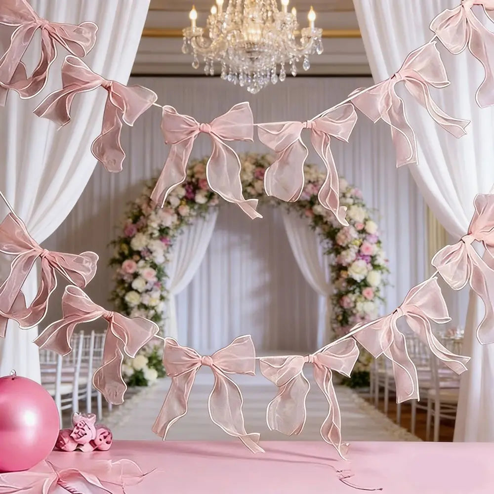 Pink sheer ribbon bow knot banner garland decorating a wedding or party backdrop