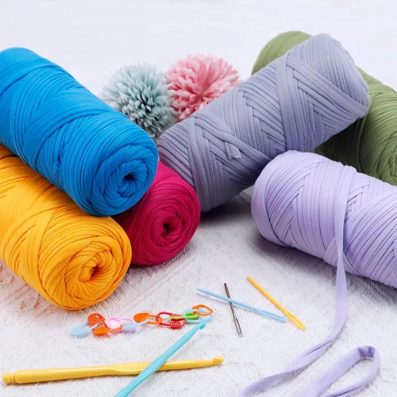 A collection of thick polyester blend yarn in various colors including blue, orange, pink, purple, and green, laid out on a w