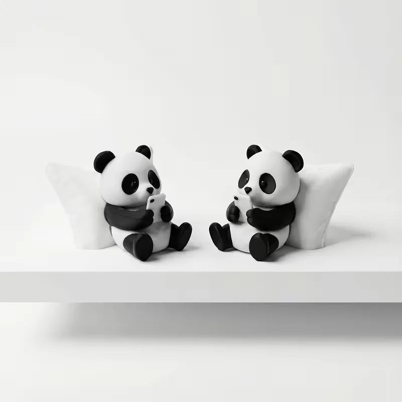A pair of cute black and white panda figurines sitting on a white surface.
