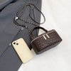 A dark brown woven PU leather crossbody bag rests next to a light-colored smartphone and a gray blazer.
