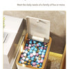 A gold-colored pop-up slim trash can is shown open, filled with colorful spherical items, on a marble surface.