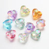 A collection of twenty acrylic heart-shaped beads in various shades of pink, purple, and yellow.