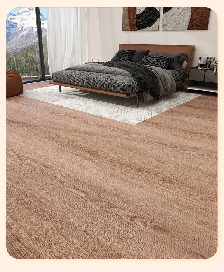 A bedroom interior featuring a wooden bed frame, dark bedding, and a light rug on a wood-grain floor.