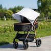 A black stroller with a white sun shade is shown outdoors on a paved path.