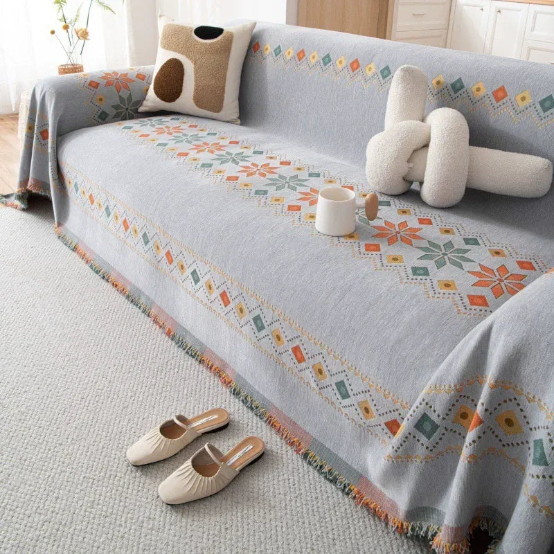 A light gray bohemian jacquard sofa cover featuring geometric patterns and decorative tassels.