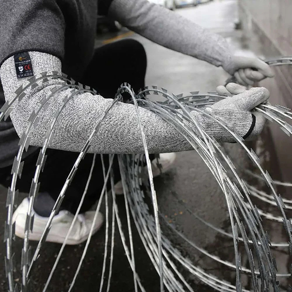 A person wearing protective arm sleeves is handling a bundle of thin, metallic wires.