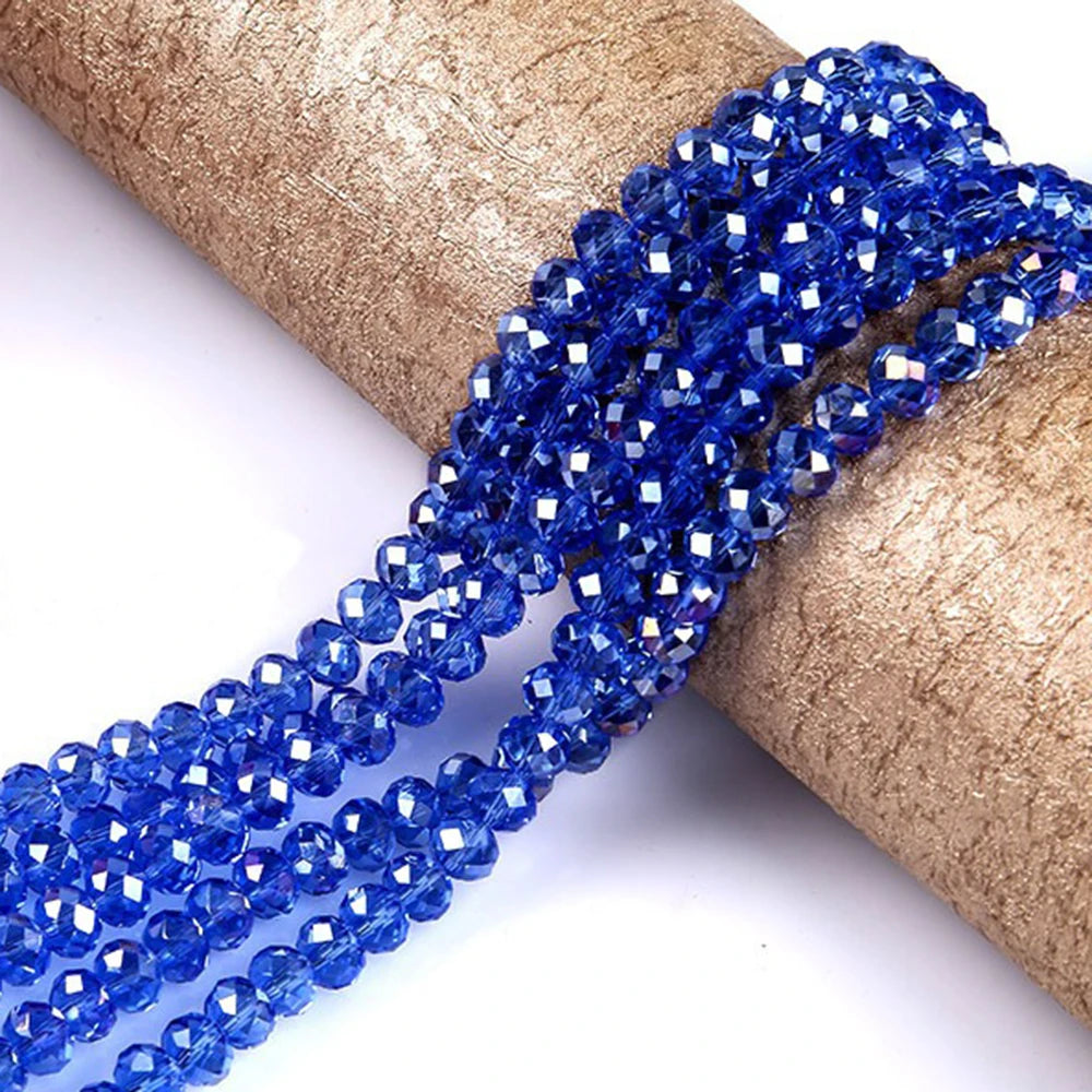 Blue faceted crystal glass spacer beads threaded onto a golden brown paper roll.
