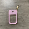 A pink silicone protective case for a hand sanitizer spray attached to a gold keyring.