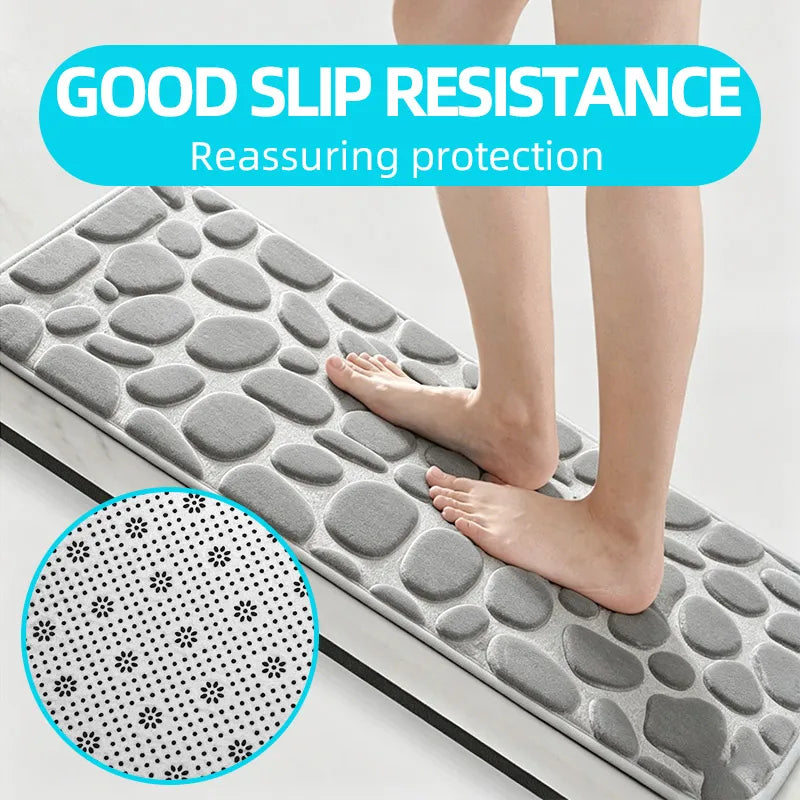 A person's feet resting on a gray, pebble-textured non-slip bathroom mat with a dotted pattern detail.