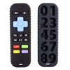 A black silicone baby teether toy shaped like a remote control with various buttons and numbers.