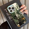 A phone case featuring a monstera plant pattern is shown resting on a dark notebook.
