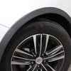 Close-up view of a black alloy wheel with a tire and carbon fiber-look arch trim.