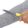 A hand holds a knife inserted into a gray and black textured arm sleeve for industrial safety.