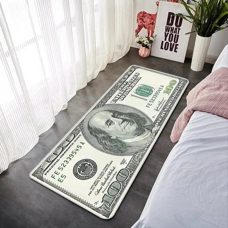 A US dollar banknote lying on a gray floor mat next to a white window and a pink plant.