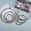 A set of three wooden embroidery hoops with white and brown rims displayed next to a book.