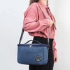 A woman holds a navy blue insulated lunch bag with a shoulder strap against a white background.