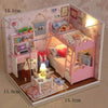 A miniature pink wooden dollhouse building kit featuring a bed, furniture, and decorative elements.
