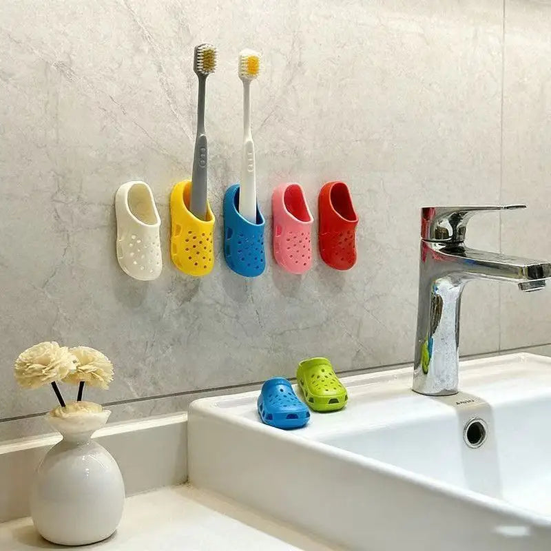 A collection of adhesive wall-mounted toothbrush holders in various colors mounted above a white sink.